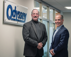 Bob Shellman, President and CEO (left); Cosmo Alberico, EVP, COO and CFO (right) of Odyssey Logistics & Technology Corporation in front of company logo.