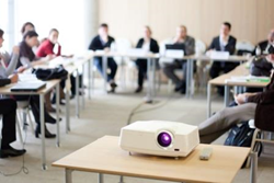 People sitting in a meeting room with a projector.