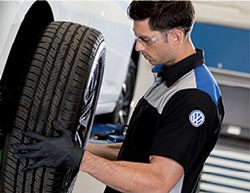 Image of a Volkswagen service technician rotating the tires of a VW vehicle