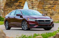 2019 Honda Insight exterior shot with dark red paint color parked beside a brick bridge
