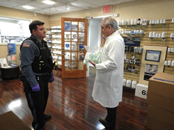 A Ridgewood Police Officer picking up hand sanitizer from John Herr, RPh., Pharmacist & Owner of Town & Country Compounding Pharmacy in Ridgewood, New Jersey.