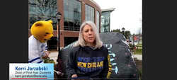 Dean Kerri Jarzabski hosting Virtual Accepted Students day in front of the Rock with SPIRIT in the background painting the Rock.