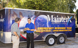 A MaintenX emergency response team members stands in front of an emergency supply truck, helping a customer.