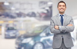 Car salesman standing in front of blurred out cars