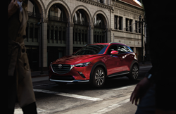 A red 2020 Mazda CX-3 parked at a city intersection.