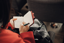 small open notebook, a hand writing down notes