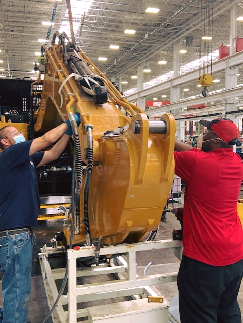 SANY manufacturing team members work on assembling an SY215C medium excavator at the headquarters in Peachtree City, Ga. while wearing appropriate PPE.