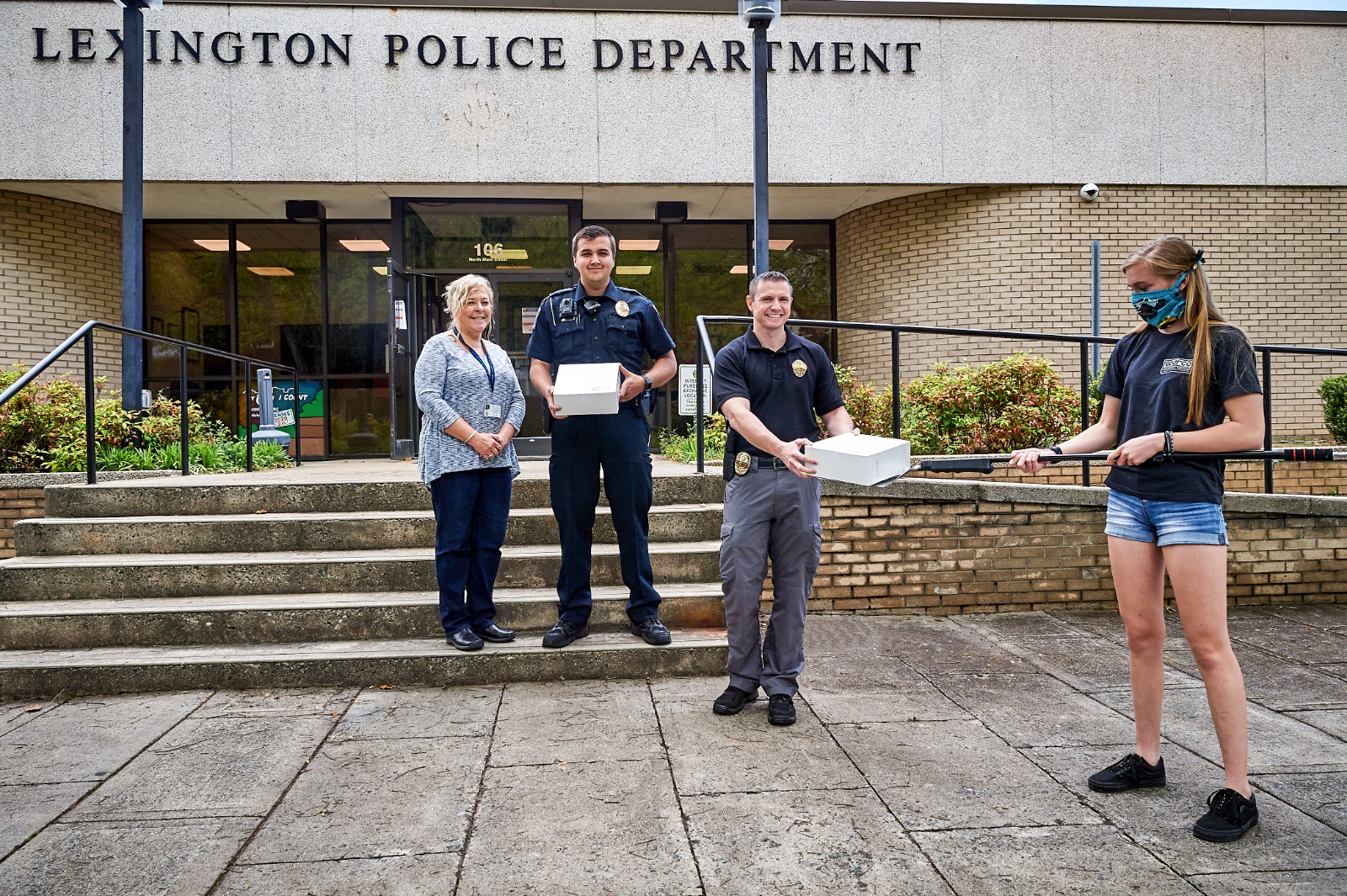 Young pro driver, Gray Leadbetter, demonstrates the "social distancing way" to deliver treats from the Red Donut Shop in Lexington, NC to local police.