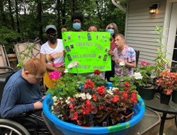 Members of an Arc of Southern Maryland group home display a sign they created thanking Melwood for their donated flowers.