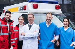 Paramedics and healthcare professionals posing in front of ambulance