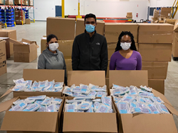 Global eBrand employees stand next to boxes of FDA approved face masks.