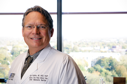 Doctor in white coat posing near window