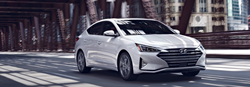 Front passenger angle of a white 2020 Hyundai Elantra driving on a road