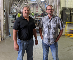 Adam Brown and Rick Rossetti stand on shop floor at their sign company