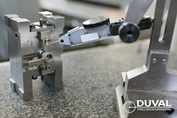 A metal probe taking measurements of a bracket sent to Duval Precision Grinding for finish grinding services.