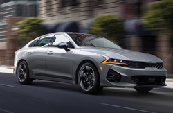 2021 Kia K5 gray driving down slanted road with motion blur
