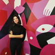 Sought-after Chicago-based fine artist and muralist, Liz Flores, poses in front of a mural she painted for Sephora