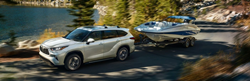 White 2020 Toyota Highlander Towing a Boat on a Lake Road