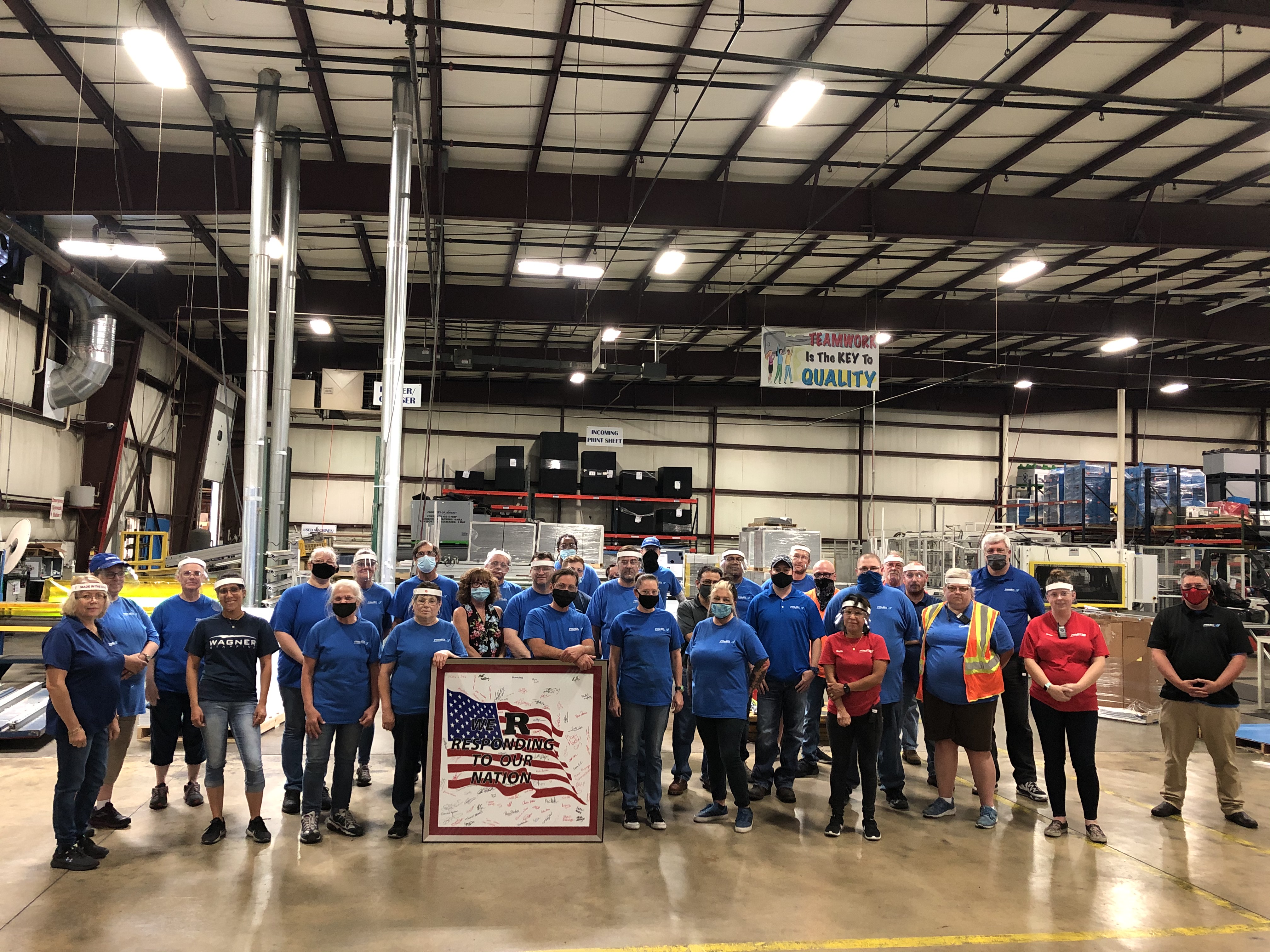 Primex employees are proud of their involvement in fighting Covid-19. They are holding an American flag they all signed during a recent shift.