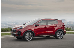 2021 Kia Sportage exterior side view with dark red paint parked on a hill with a fog city background