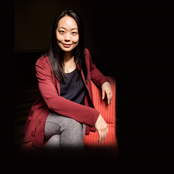 Dr. Peii Chen, sitting on a chair against a black background