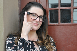 A woman wearing OrCam MyEye and pointing to the device.