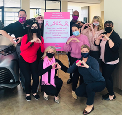 The Toyota of Puyallup staff posing around a sign that promoted their Breast Cancer Awareness efforts during the month of October.