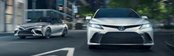 2021 Toyota Camry Hybrid XSE and XLE models exterior shot driving through a city a night