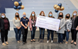 Winner holding her large check with colleagues standing on either side of her