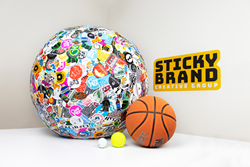 Guinness World Records largest Ball of Stickers next to tennis ball, basketball and golf ball.