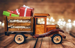 wooden toy truck with Christmas presents inside and lights in the background