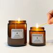 Hand lighting two WANDERNESS scented candles