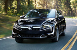 2021 Honda Clarity Plug-In Hybrid exterior shot with Crystal Black Pearl paint color driving through a forest highway