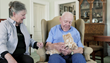 elderly man holds orange tabby animatronic cat