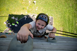 Photo from Confidence Camp 2020. Camper enjoys climbing MMA's 40-foot rock wall.
