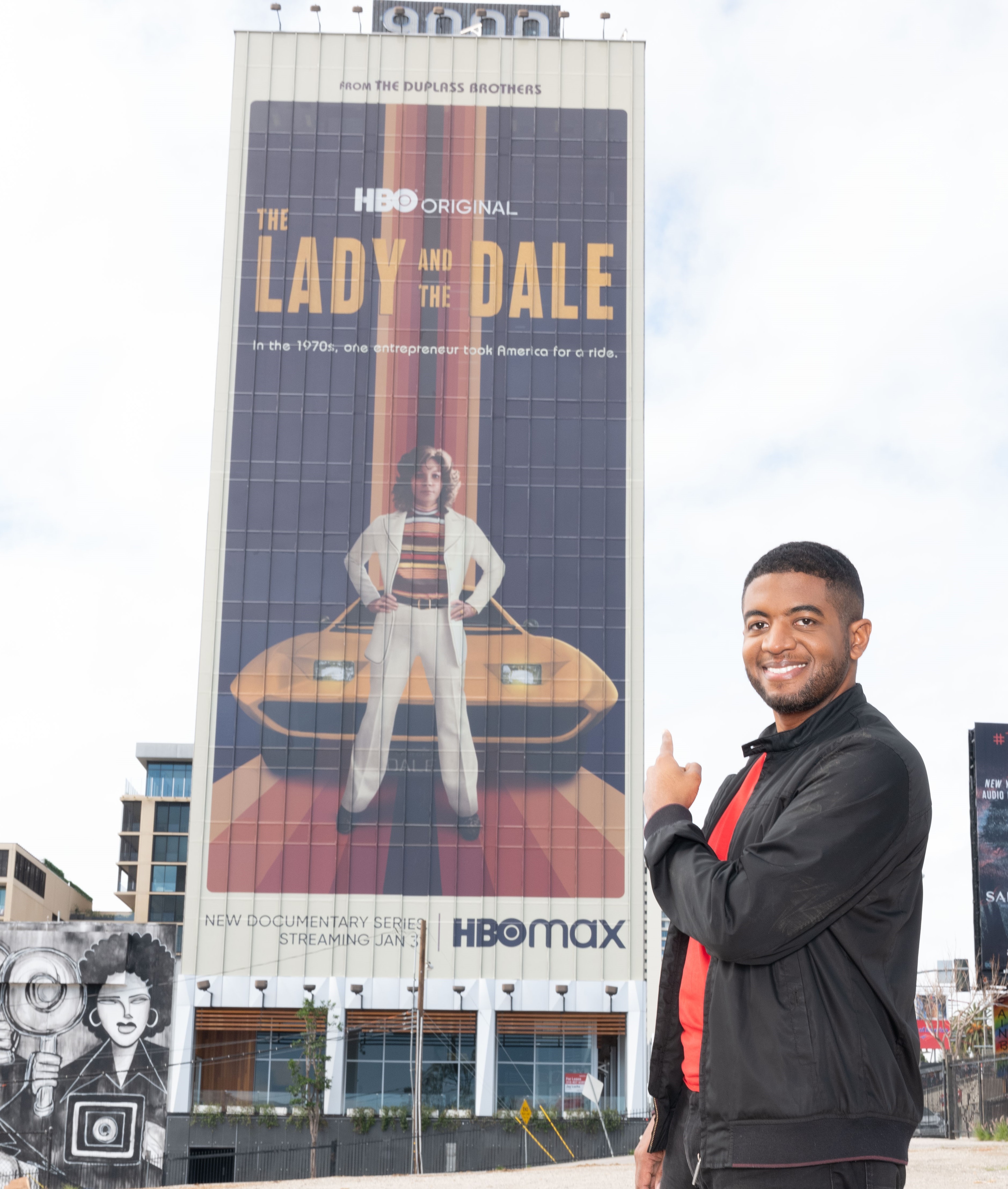 Film and Television Producer Andre Gaines of Cinemation Studios Poses in front of The Lady and The Dale Billboard on Sunset Strip - cropped