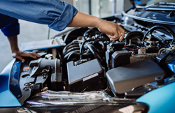 an auto mechanic working on an engine under the hood of a motor vehicle