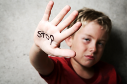 child being abused with his hand that says stop in black marker