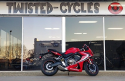 The side view of a red pre-owned 2019 Honda CBR650 parked in front of the Twisted Cycles dealership.