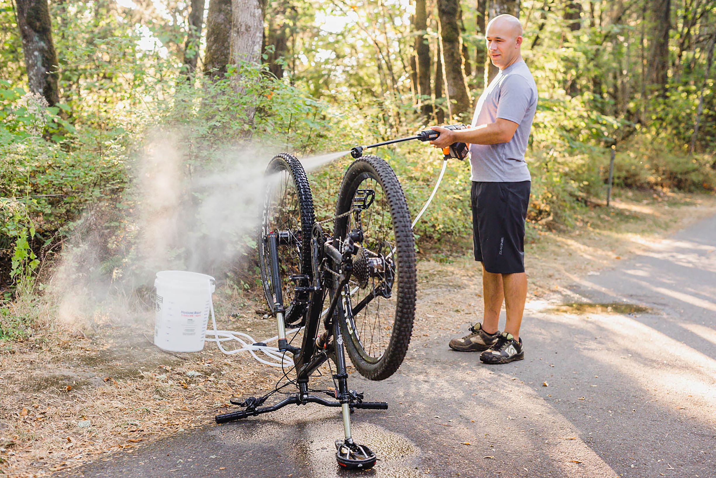 WORX Hydroshot draws fresh water from a bucket through a 20 ft., accessory hose to clean bike on trail.