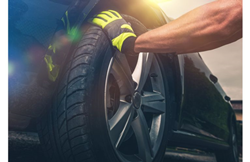 person holding tire of blue car