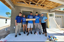 Five MaintenX team members all dressed in blue shirts pose outside the under-construction Horton home in Clearwater, FL.