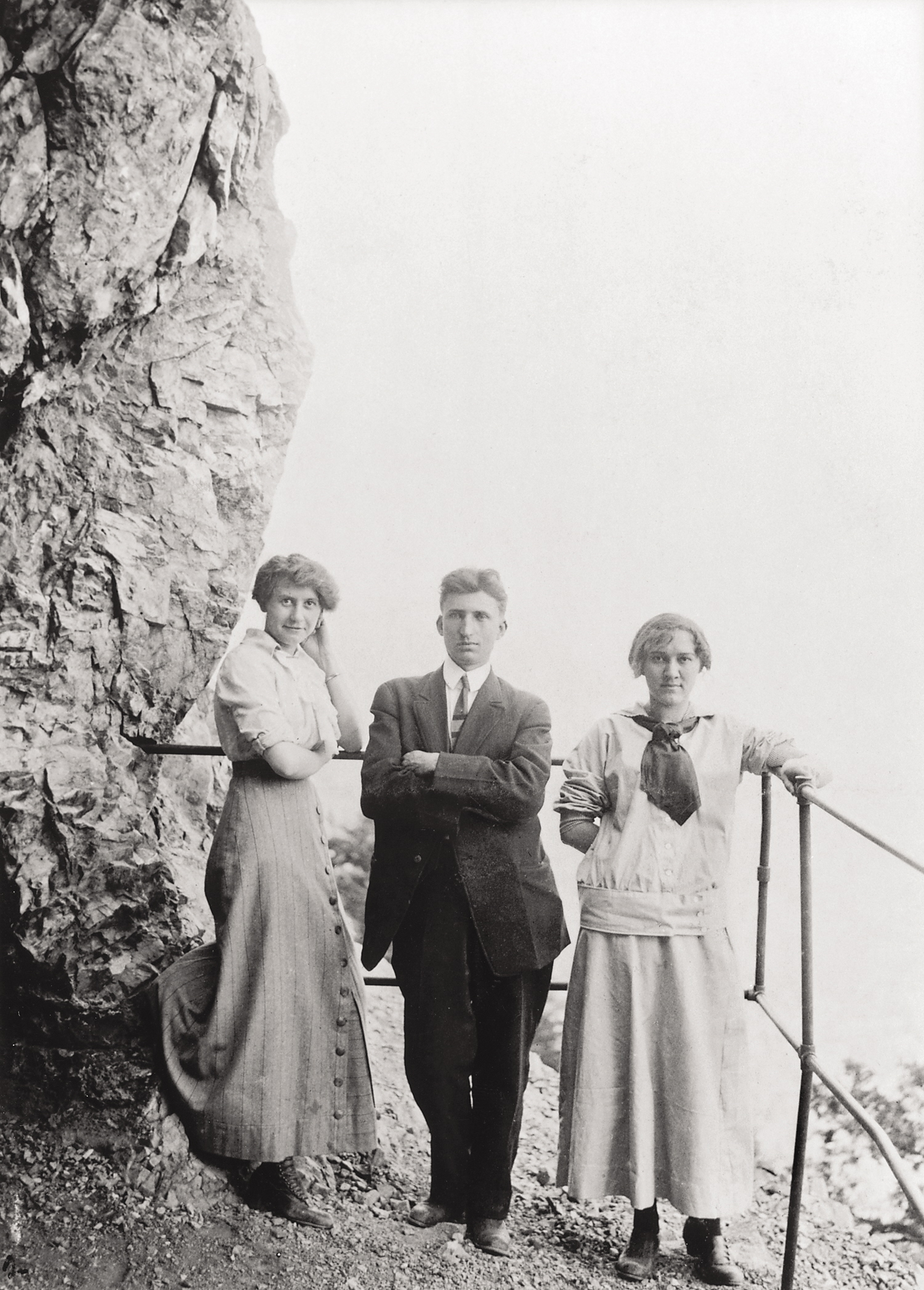 Historic black-and-white photo of three fashionable young people standing on Exclamation Point, a viewing platform that today’s visitors also can stand on high up the side of the Rocky Mountains overl