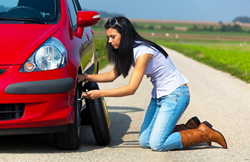 a woman changing a red car's tire