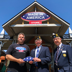 Made In America Store Founder & CEO, Mark Andol, handing off a folded U.S.A. flag to veterans