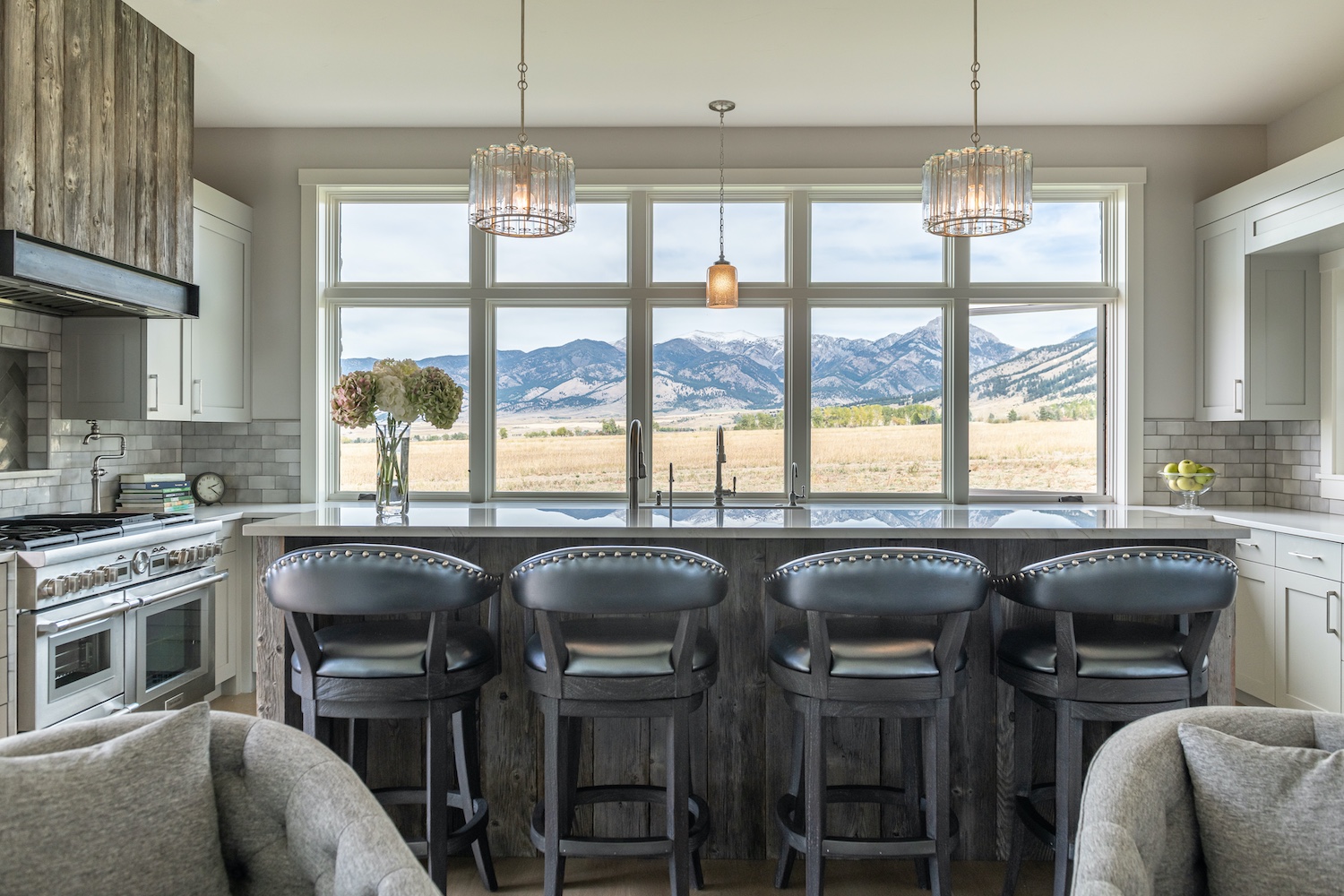 Rustic wood on the custom range hood complements the clean-lined white kitchen dominated by spectacular Montana mountain views (photo: Audrey Hall).