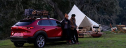 2021 Mazda CX-30 red exterior passenger side rear fascia couple camping in the woods