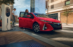 2021 Toyota Prius Prime red charging on city street