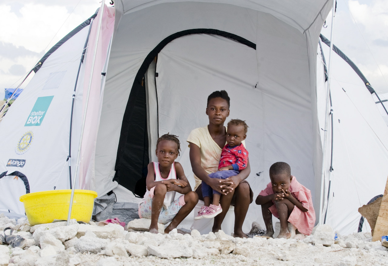 A family in Haiti sits outside of ShelterBox relief tent they received, Haiti, 2010.