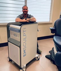 Joe Gatti, PA-C, smiles while standing behind the brand new EMSCULPT NEO device at The Clinic.